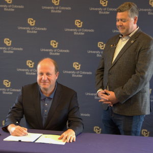 Colorado General Assembly Representative Alex Valdez (right) watches as Colorado Governor Jared Polis signs the Quantum Tax Credit Bill