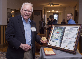 Photograph of Jan Hall with framed award.