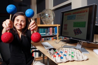 Ana Maria Rey holding up models of atoms.