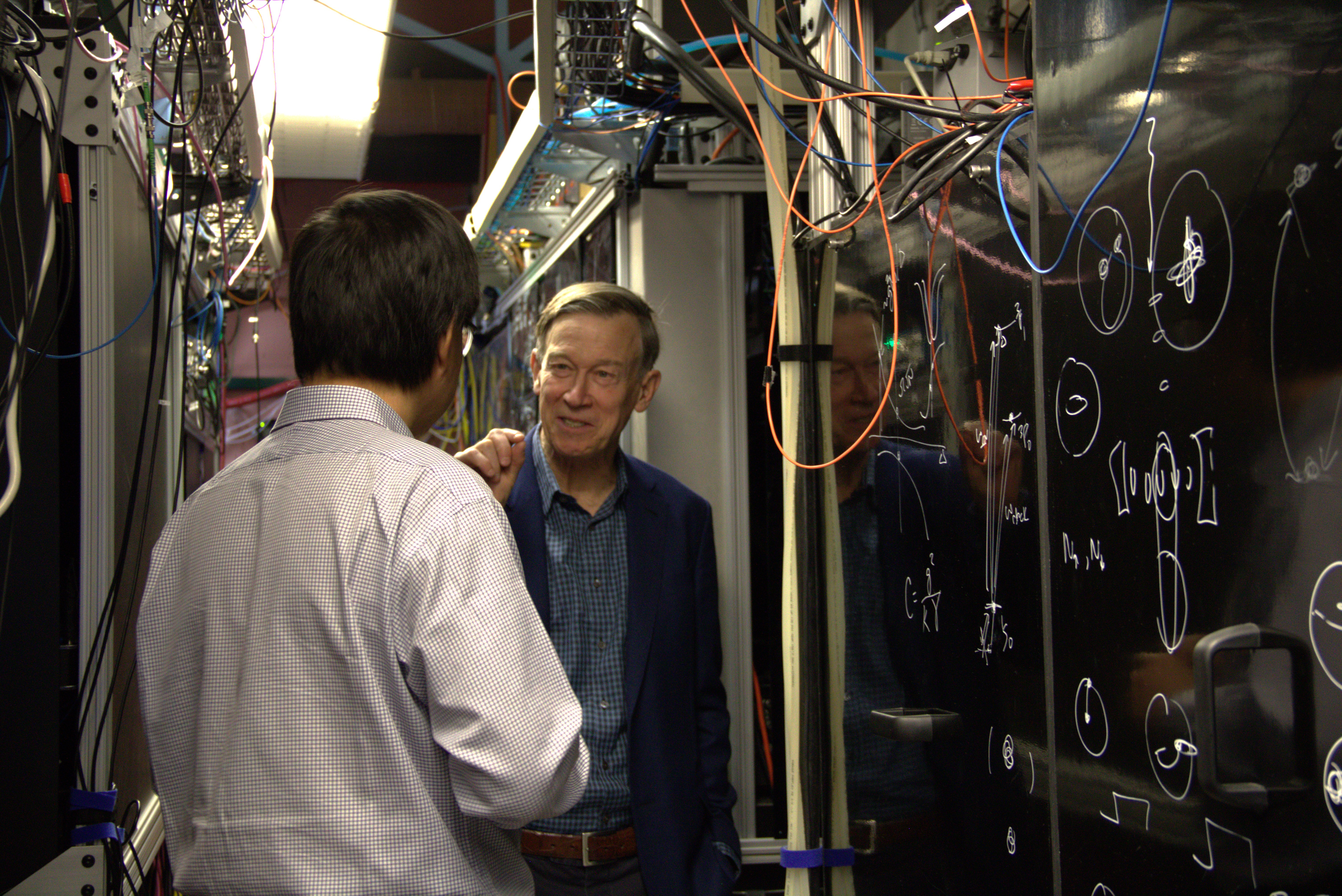 Senator Hickenlooper (right), discusses the importance of atomic clocks with JILA and NIST Fellow Jun Ye (left)